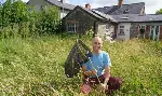 Photo of Jesmond Harding crouching in a grassy lawn and holding a butterfly net